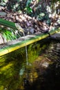 A closeup of a traditional Asian bamboo fountain with water splashing in the pool Royalty Free Stock Photo