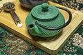 Closeup of traditional Chinese cast iron green teapot with green cloth background, copper saucepan Royalty Free Stock Photo