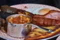 Closeup of traditional tasty scottish english breakfast consisting of beans, sausage, bacon, mushrooms, egg and a black pudding.