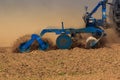 closeup trailer of cultivator raises dust on ploughed field