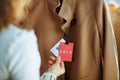 Closeup on trendy female examines sale price tag on beige coat