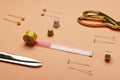 Closeup of trndy set of sewing tools.Measuring tape, pins, thimbles and scissors on the orange desk Royalty Free Stock Photo