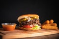 Closeup of Tsaty Cheeseburge sandwich, cheese sticks and Onion rings on wooden table Royalty Free Stock Photo