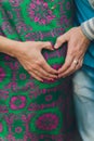 Closeup on tummy of pregnant woman, wearing long green dress, holding in hands bouquet of daisy flowers outdoors, new Royalty Free Stock Photo