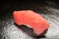 closeup of a tuna sushi. Japanese Nigiri sushi with raw tuna fillet. Maguro sashimi with rice on black stone background Royalty Free Stock Photo