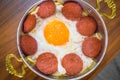 Closeup of Turkish sausage (sucuk) and fried egg in copper pan on wooden table