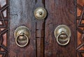Closeup of two antique copper ornate door knockers over an aged wooden door Royalty Free Stock Photo