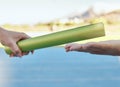 Closeup of two athletes passing a baton during a relay race on a running track. Active fit athlete handing the baton