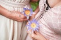 Closeup of two Caucasian females holding purple Selenicereus Grandiflorus flowers