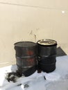 Closeup of two dirty greasy barrels outside building in snow. Royalty Free Stock Photo