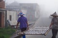 Closeup of two fishermen carrying their drying fish. Zhangzhou, China.