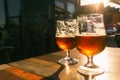 Closeup of two glasses of beer on terrace table with evening sun shining through them. Relaxation, food and drink concept with