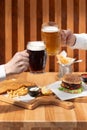 Closeup of two hands clinking beer stein glasses. Toasting with a pint of draft beers on counter at pub Royalty Free Stock Photo