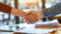 A closeup of two individuals shaking hands with a stack of immigration documents resting on a nearby table Royalty Free Stock Photo