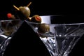 Two martinis on black with olives