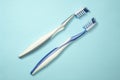 Closeup of two new plastic toothbrushes on a blue background.