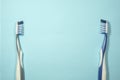 Closeup of two new plastic toothbrushes on a blue background.