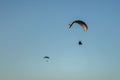 Closeup of two paragliders paragliding in the sky