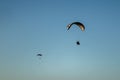 Closeup of two paragliders paragliding in the sky