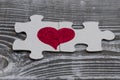 Closeup of two pieces of a puzzle forming a heart on a rustic wooden surface, Royalty Free Stock Photo