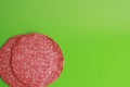 Closeup of two slices of salami on a green surface