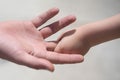 Closeup of two touching hands of small baby boy holding finger of male father as symbol of family love and trust on Royalty Free Stock Photo