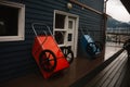 Closeup of two wheelbarrows leaning on a wooden building wall during the rain