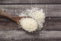 Closeup uncooked dry Thai jasmine rice are overflow in wooden ladle on wooden floor, flat lay and top down horizontal view.