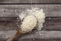 Closeup uncooked dry Thai jasmine rice are overflow in wooden ladle on wooden floor, flat lay and top down horizontal view.