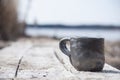 Closeup of unique handmade cup with folk sign with blurred lake on background