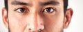 Closeup of an unknown asian mans face and eyes looking forward and into the camera. Zoom headshot of a mixed race man Royalty Free Stock Photo
