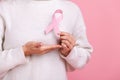 Closeup of unknown female holding pink ribbon, symbol of breast cancer awareness, cancer prevention.