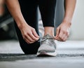 Closeup of unknown trainer tying shoelaces alone in gym. One caucasian coach kneeling, getting ready to workout health