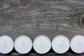 Closeup of unlit white tea candles on dark rough wooden table background outdoors. Top view, copy space