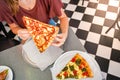 Closeup unrecognizable friends eating delicious pizza slices indoor.