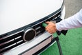 Man hand holding socket plugged into electric car Royalty Free Stock Photo