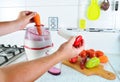 Closeup. Unrecognizable man presses carrot inside juicer to make tasty juice for breakfast from fresh vegetables, pours in