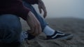 Closeup unrecognizable man sitting on beach. Young guy holding wet sand in hand