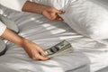 Woman hiding money under pillow at home