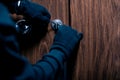 Robber in black mask cracking door with metal picklock