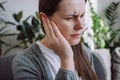 Closeup up side profile of sick young caucasian female having ear pain touching painful head sitting on sofa. Unhealthy woman 20s Royalty Free Stock Photo