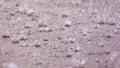 Large raindrops create multiple splashes on a concrete patio on of a house.