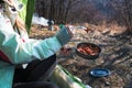 Closeup up view of a woman in mountains in tent eating pasta from a pot prepared on wood burner Royalty Free Stock Photo
