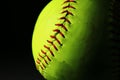 Closeup of a bright, yellow softball with red seams. Royalty Free Stock Photo