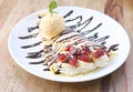 Close up of vanilla ice cream with crepes and strawberry on wooden desk Royalty Free Stock Photo