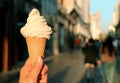 Vanilla Soft Serve Ice Cream Cone in Hand with Blurry Walking Street in Backdrop Royalty Free Stock Photo