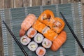 Closeup of various kinds of sushi rolls with salmon, sashimi and other slices of raw fish and a pair of wooden chopsticks served Royalty Free Stock Photo