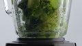 Closeup vegetables dropped blender with spinning blades in super slow motion