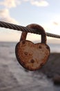 Closeup vertical shot of a rusty weathered heart-shaped padlock hanging from a rope Royalty Free Stock Photo