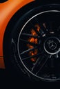 Closeup vertical shot of the wheel of an orange luxury Mercedes-Benz AMG SL